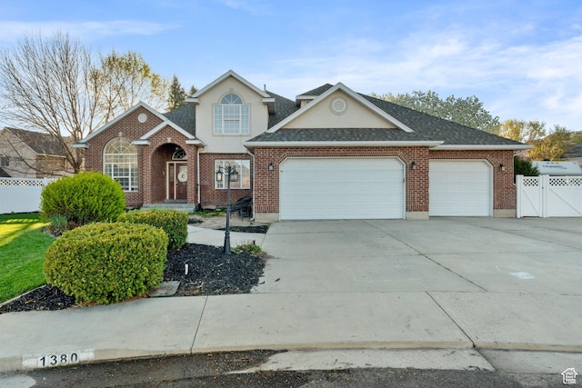 traditional-style home with concrete driveway, an attached garage, fence, stucco siding, and brick siding