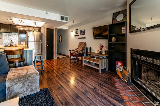 living room with a fireplace with flush hearth, wood finished floors, and visible vents