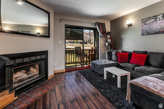 living area featuring a tile fireplace, baseboards, and wood finished floors