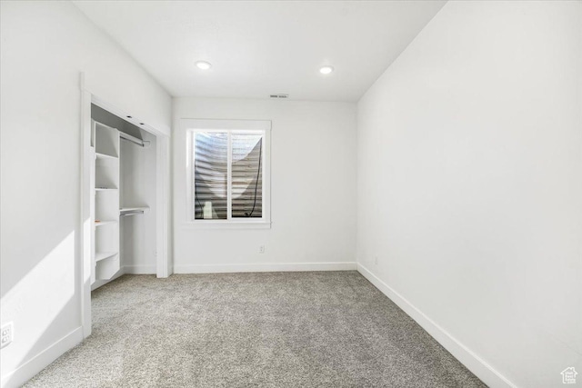 unfurnished bedroom with a closet, carpet floors, visible vents, and baseboards