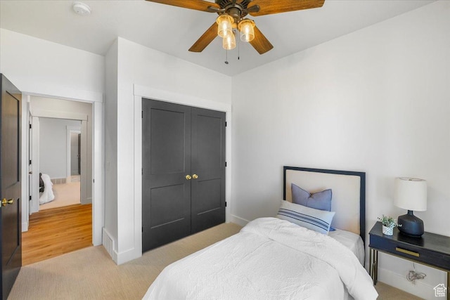 bedroom featuring ceiling fan, baseboards, a closet, and light colored carpet