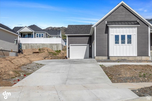 view of front of house featuring a standing seam roof, driveway, fence, an attached garage, and board and batten siding
