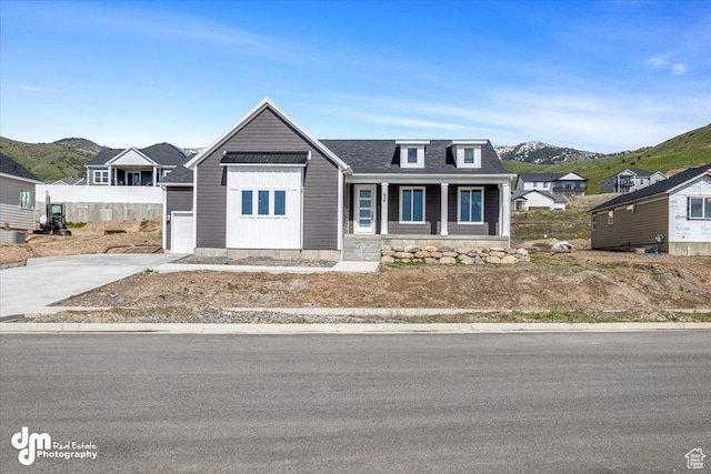 view of front of house with roof with shingles, driveway, covered porch, and a mountain view
