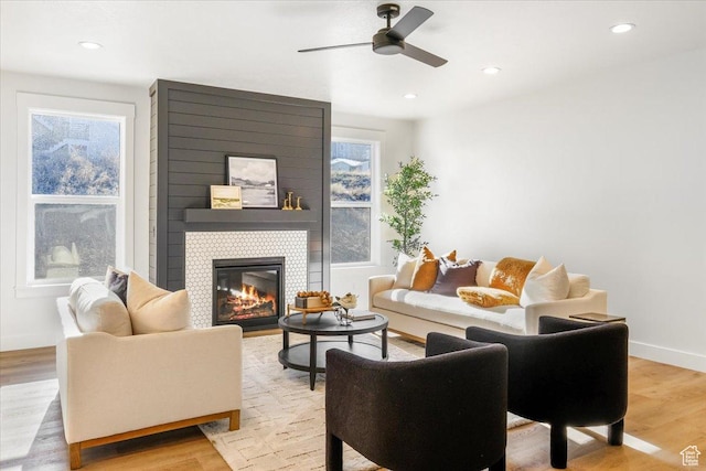 living area featuring a fireplace, light wood-type flooring, a ceiling fan, and recessed lighting