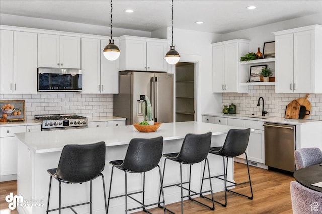 kitchen with a kitchen breakfast bar, open shelves, backsplash, a sink, and appliances with stainless steel finishes