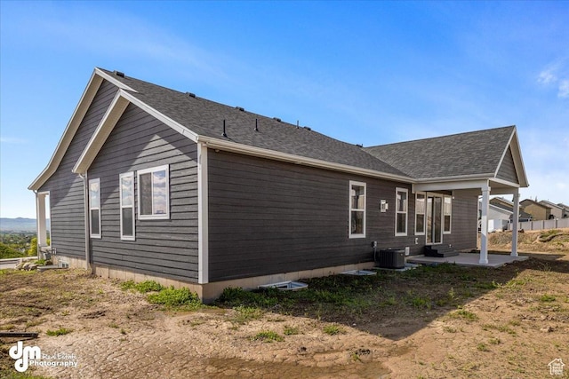 view of property exterior with a patio area, roof with shingles, and cooling unit
