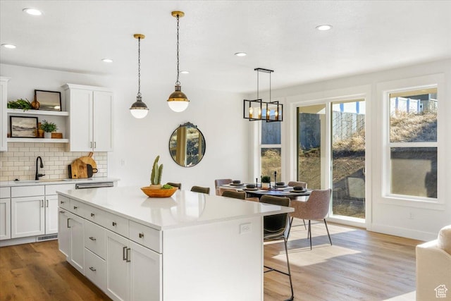 kitchen featuring a kitchen breakfast bar, a sink, backsplash, open shelves, and light countertops