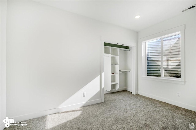 unfurnished bedroom featuring baseboards, visible vents, carpet floors, and a closet