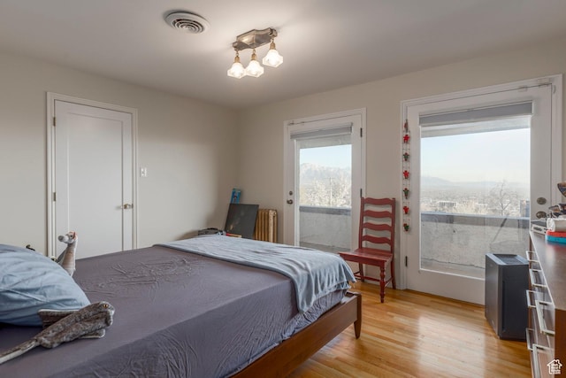 381 E 11th Ave, Salt Lake City, UT 84103 - bedroom with radiator heating unit, light wood-style flooring, visible vents, and access to exterior