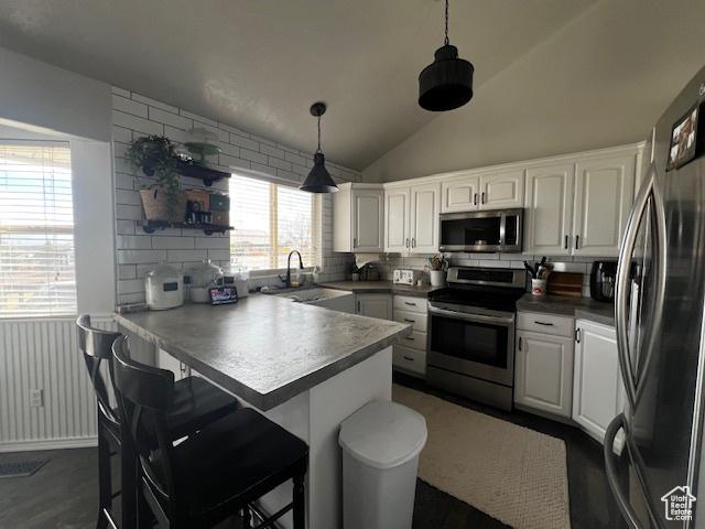 1115 Park Ridge Dr, Roosevelt, UT 84066 - kitchen featuring white cabinets, a peninsula, a sink, a kitchen bar, and appliances with stainless steel finishes