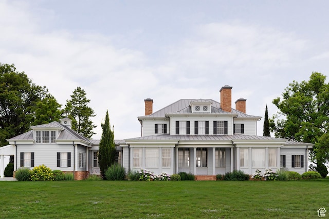 view of front of home featuring a front yard, a chimney, a standing seam roof, and metal roof