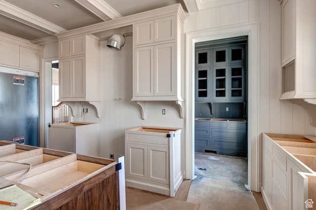 kitchen with light countertops, a decorative wall, fridge, and ornamental molding