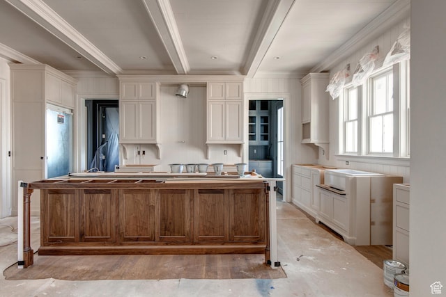 kitchen with beamed ceiling, crown molding, a center island, and white cabinetry