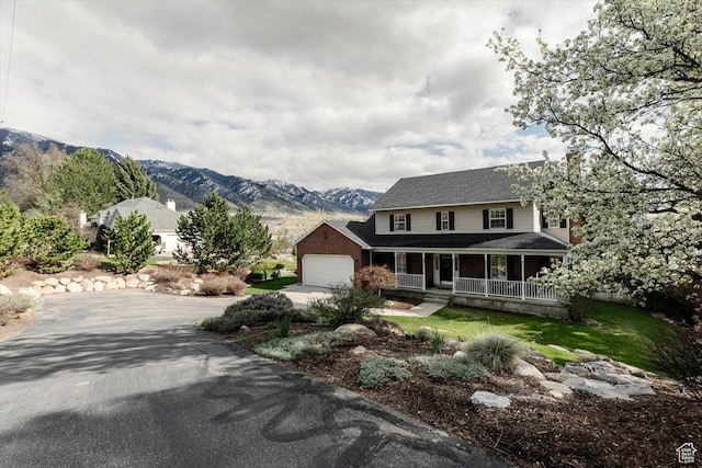 770 Orchard Dr, River Heights, UT 84321 - farmhouse with a mountain view, a porch, concrete driveway, an attached garage, and a shingled roof
