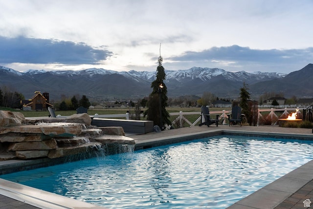pool featuring a patio area, an outdoor fire pit, and a mountain view