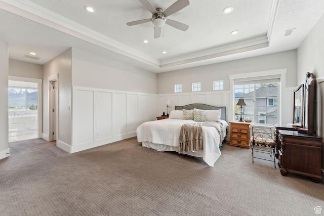 bedroom featuring recessed lighting, a tray ceiling, a ceiling fan, a decorative wall, and carpet flooring