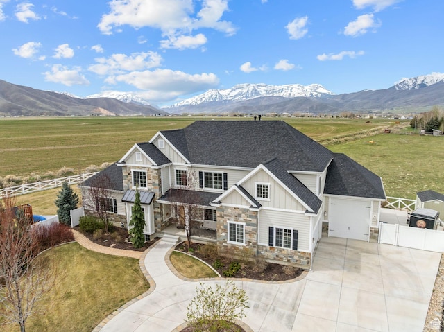 craftsman inspired home featuring driveway, fence, stone siding, and board and batten siding
