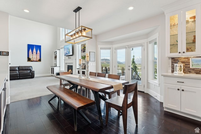 dining room with recessed lighting, dark wood finished floors, baseboards, and a lit fireplace