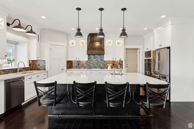 kitchen with premium range hood, dark wood finished floors, stainless steel appliances, and a sink