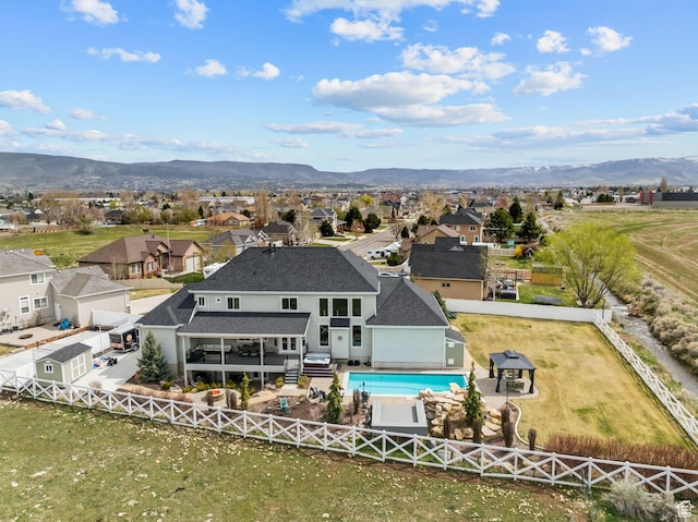 rear view of house with a fenced backyard, a mountain view, a residential view, and a shingled roof