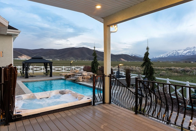 view of swimming pool featuring a deck with mountain view, a fenced in pool, a fenced backyard, a gazebo, and a jacuzzi