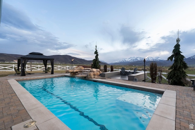 pool featuring a gazebo, a patio area, fence, and a mountain view