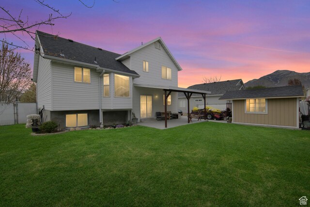 1426 N Quincy Ave, Ogden, UT 84404 - back of house at dusk featuring a patio area, a lawn, and fence