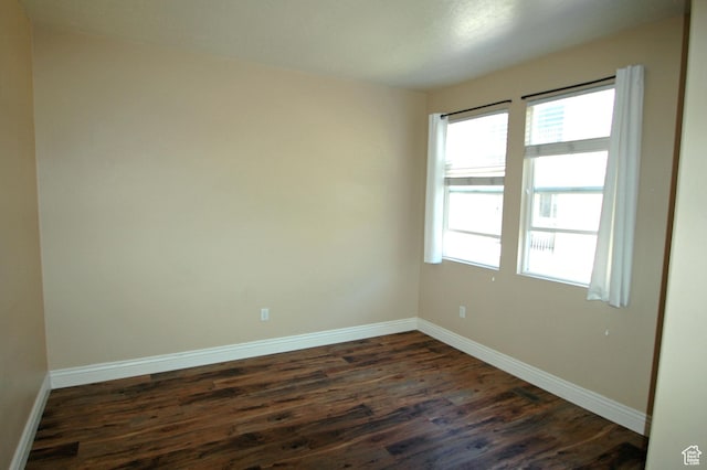 spare room featuring baseboards and dark wood-style floors