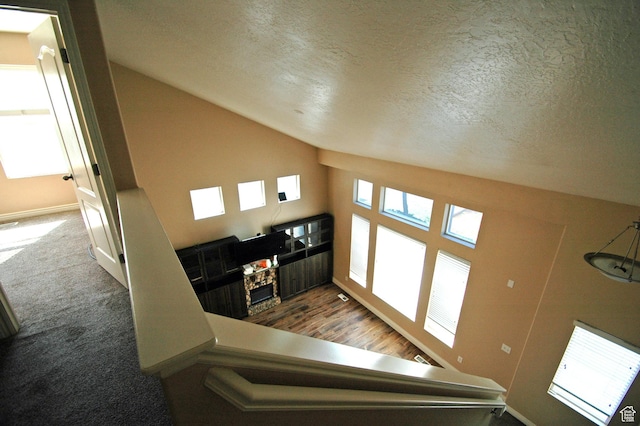 stairway featuring baseboards, a textured ceiling, and vaulted ceiling