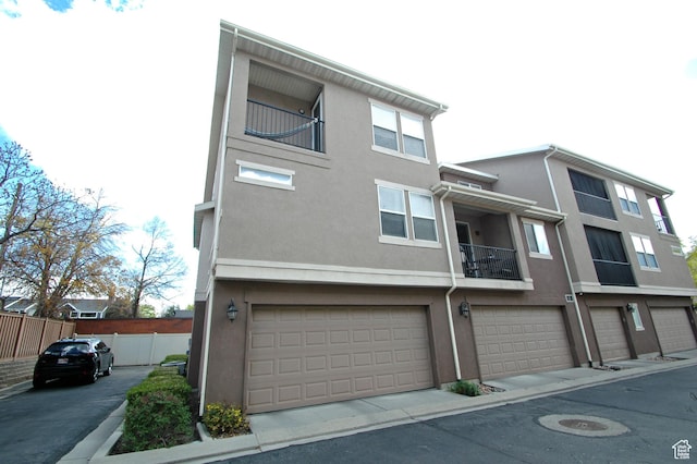 multi unit property featuring fence, a garage, and stucco siding