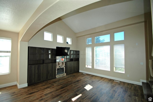 unfurnished living room featuring dark wood-style flooring, a fireplace, baseboards, and high vaulted ceiling