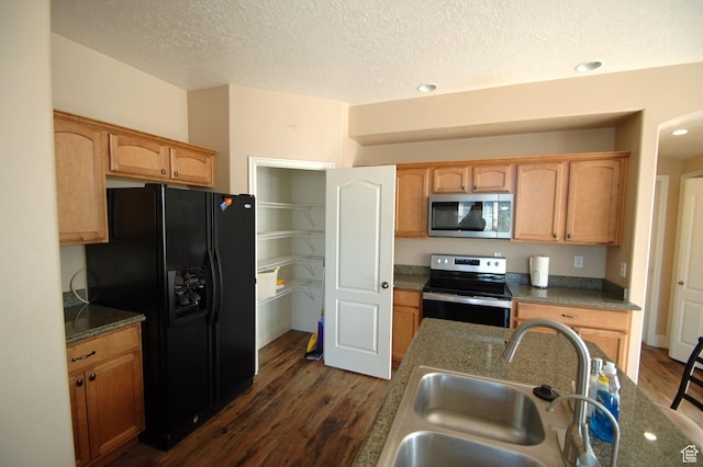 kitchen featuring a textured ceiling, stainless steel appliances, dark wood-type flooring, and a sink
