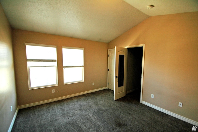 empty room with baseboards, lofted ceiling, and dark carpet