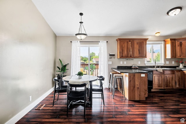 818 W 530 S, Logan, UT 84321 - kitchen featuring dark countertops, brown cabinetry, a breakfast bar area, dark wood-style floors, and a peninsula