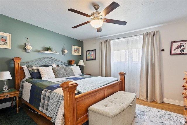 bedroom featuring baseboards, wood finished floors, and ceiling fan