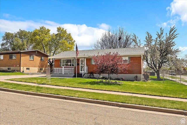 ranch-style house with fence, concrete driveway, covered porch, brick siding, and a front yard