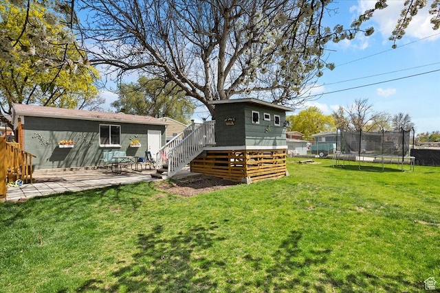 back of house with a deck, a yard, stairs, and a trampoline