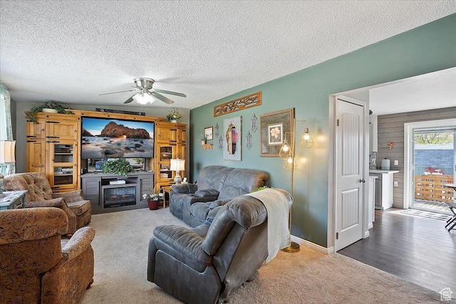 living room with ceiling fan, a fireplace, a textured ceiling, and carpet