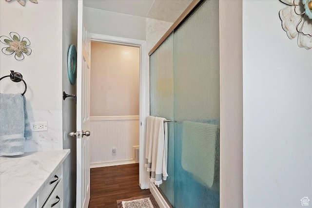 bathroom featuring wainscoting, wood finished floors, vanity, and a stall shower