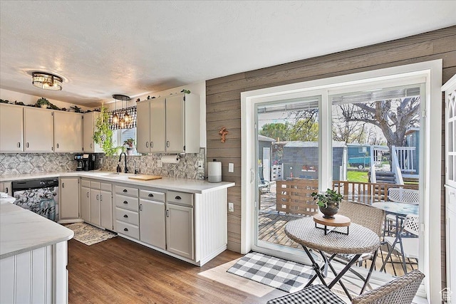 kitchen with dishwasher, light countertops, dark wood-type flooring, and tasteful backsplash