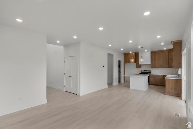 556 N 800 W, Smithfield, UT 84335 - kitchen featuring a sink, open floor plan, brown cabinets, a kitchen island, and stainless steel gas range oven