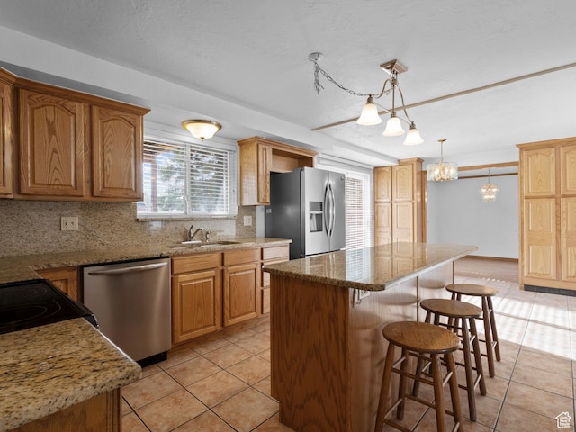 kitchen featuring a breakfast bar area, a sink, appliances with stainless steel finishes, and light tile patterned flooring