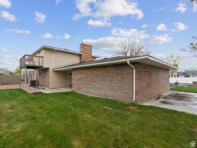 back of property featuring a chimney, fence, brick siding, a patio area, and a lawn
