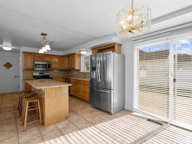 kitchen featuring a center island, a chandelier, stainless steel appliances, backsplash, and visible vents