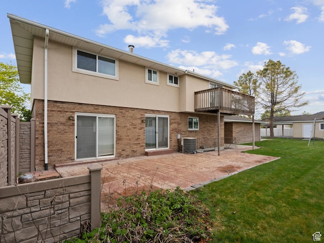 rear view of property featuring central AC unit, a patio area, a lawn, fence, and brick siding