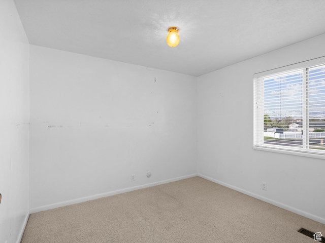 spare room featuring carpet, visible vents, and baseboards