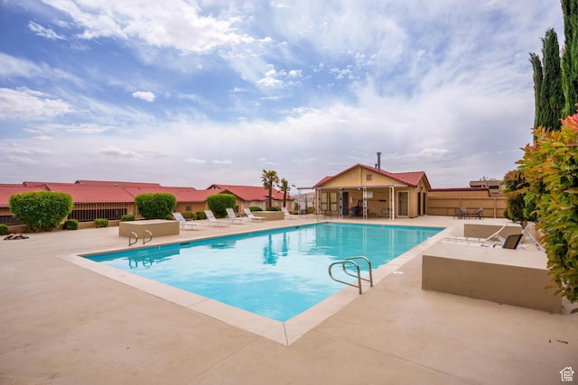 pool with a patio and fence