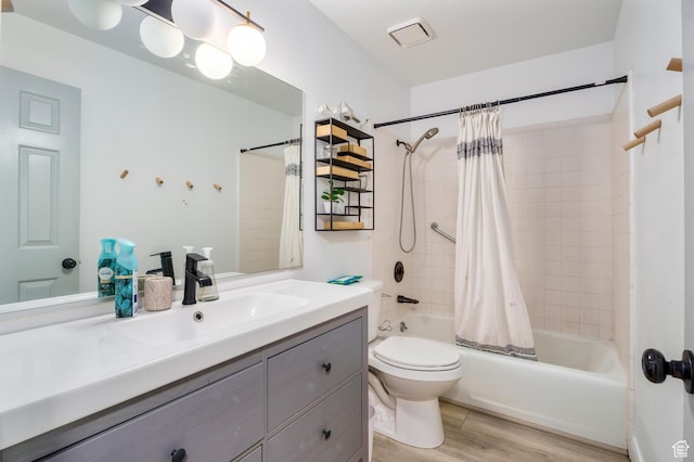bathroom featuring shower / bath combination with curtain, toilet, vanity, and wood finished floors