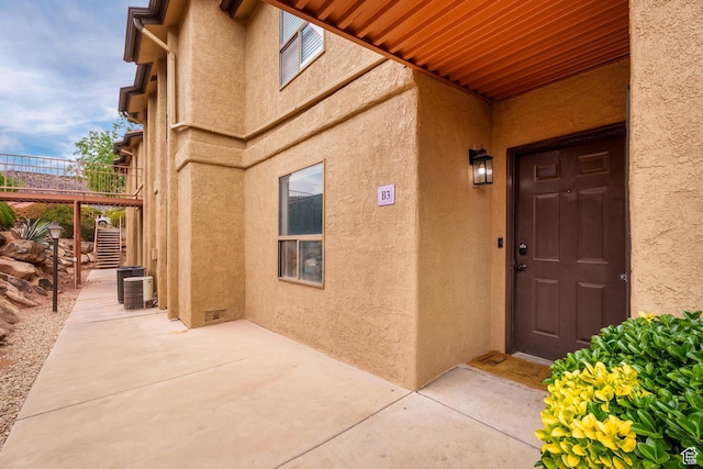 doorway to property with a patio, cooling unit, and stucco siding
