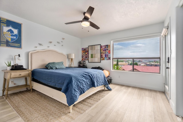 bedroom with light wood-type flooring, a ceiling fan, and baseboards